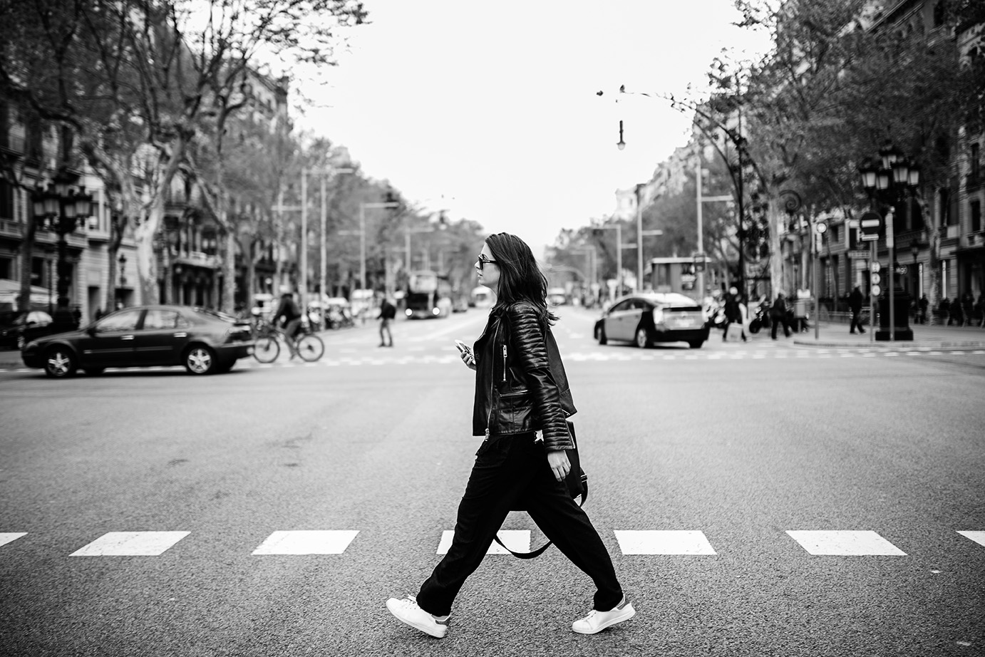 Spain, Barcelona, young woman in the city crossing street